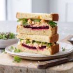 Egg salad sandwich cut in half, showing the layers of beet and egg