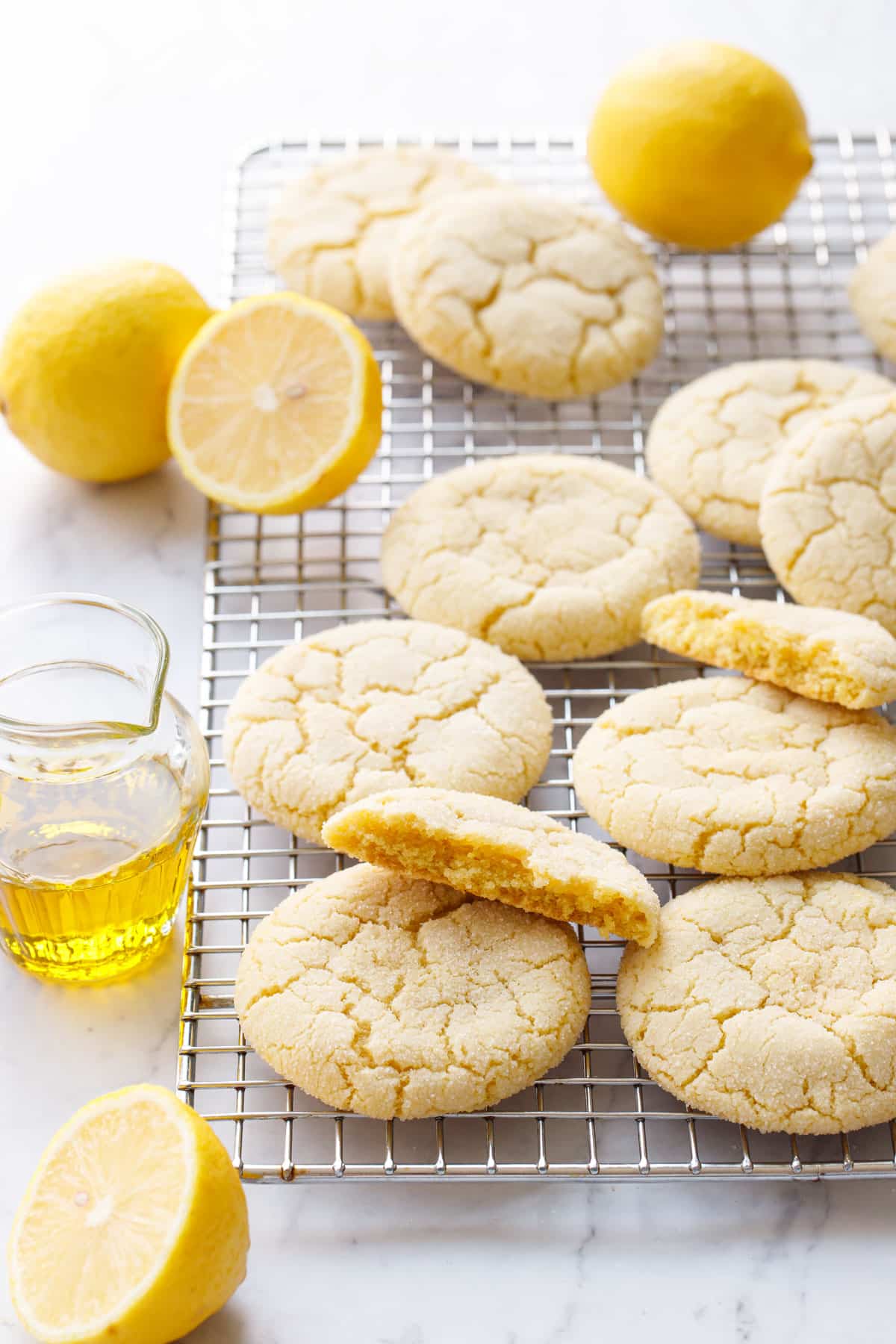 Lemon Olive Oil Sugar Cookies on a wire baking rack with crackly tops and a cookie broken in half to show the interior texture.