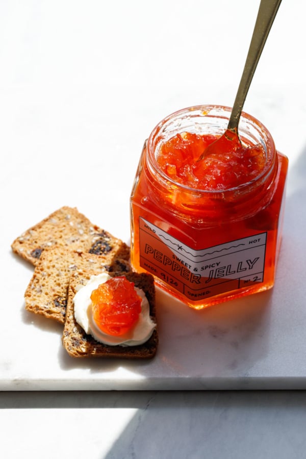 Jar of red pepper jelly with crackers and cream cheese